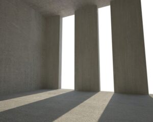 An empty city room with concrete columns and a light shining through them.