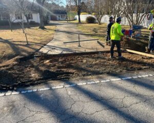 Workers repairing sidewalk near residential area.