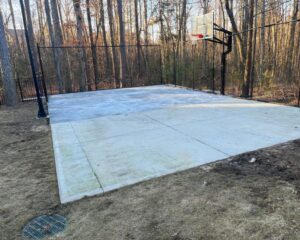 Outdoor basketball court surrounded by trees.