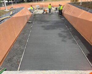 Workers paving concrete pathway in construction site.