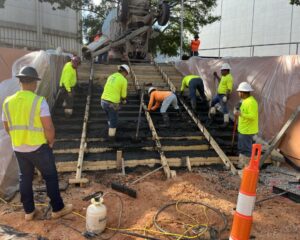 Construction workers paving concrete stairs outside.