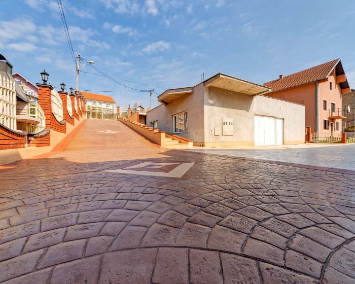 A stamped concrete sidewalk in a cityscape with houses.