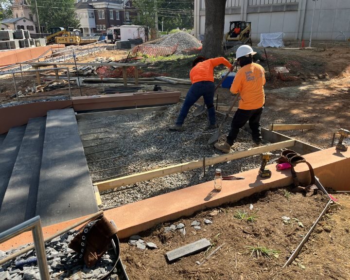 Construction workers leveling ground at building site.