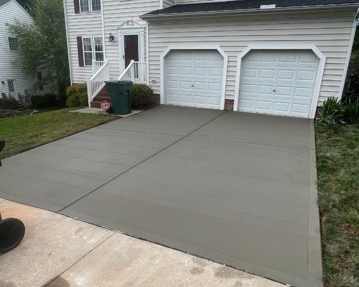 Freshly paved driveway with two white garage doors.