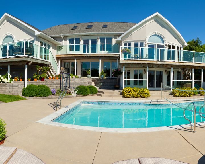 A spacious city house with a concrete pool deck and lounge chairs.