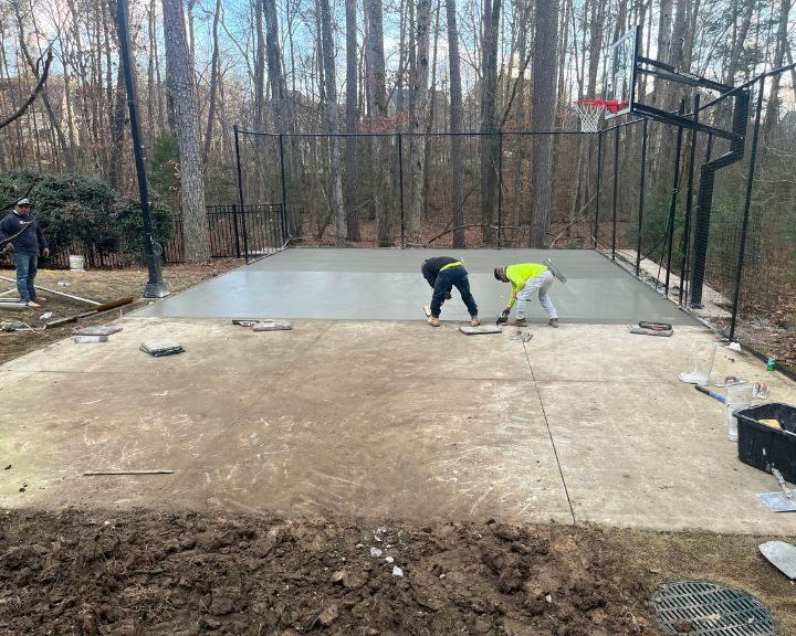 Workers finishing concrete on basketball court.