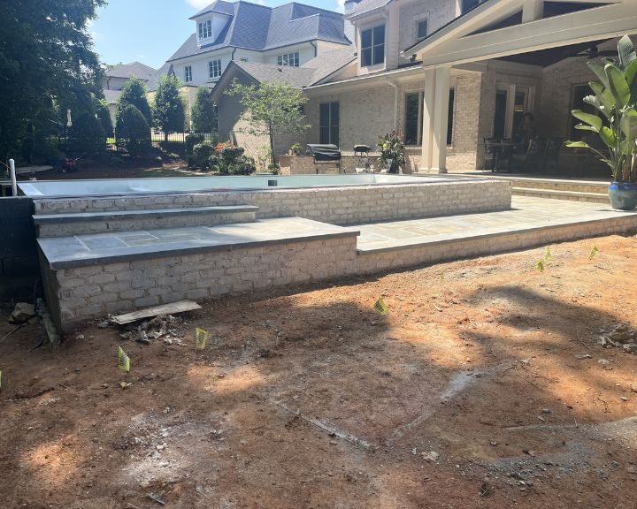 Backyard patio construction with pool in progress.