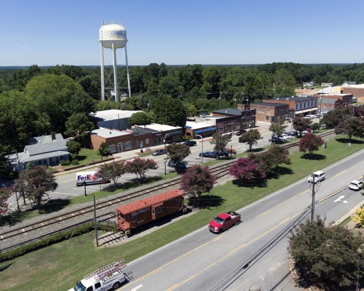 Small-town street with water tower and railroad tracks.