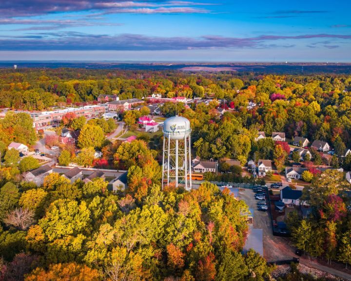 Aerial view of water tower and colorful autumn trees.