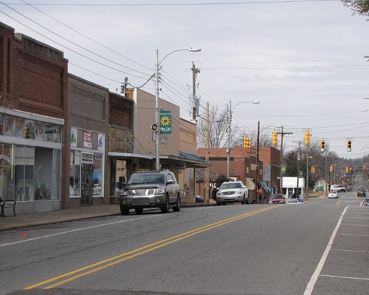 Small town street with parked cars and shops.