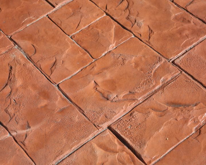 a close up view of a red brick paver resembling Stamped Concrete.